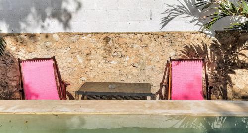 two pink chairs and a table in front of a wall at Guaya Hostel in Mérida