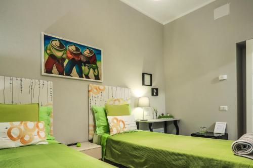 a bedroom with two green beds and a desk at Musica Guest House in Alghero