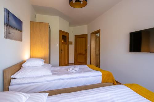 a bedroom with two beds and a flat screen tv at Willa Aga in Dębki
