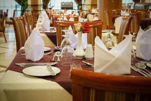 een lange tafel met witte servetten en bestek bij Saraya Harmony Hotel B in Al Madinah