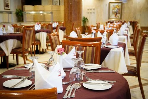een eetkamer met tafels met borden en servetten bij Saraya Harmony Hotel B in Al Madinah