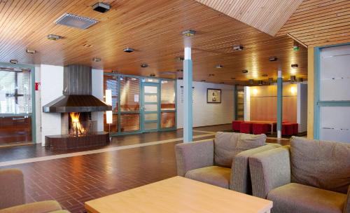 a lobby with a fireplace and chairs and a table at Saimaanranta Resort by Anttolanhovi in Mikkeli