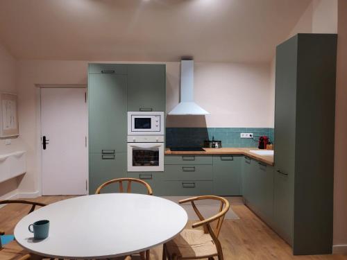 a kitchen with green cabinets and a white table at Inspiración y mar in Sagunto