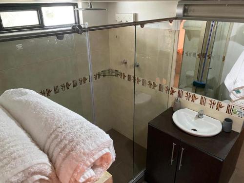 a bathroom with a glass shower and a sink at Fort House in Cali
