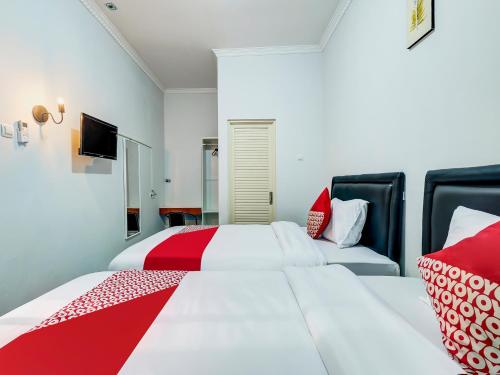1 dormitorio con 2 camas y almohadas rojas y blancas en Super OYO Capital O 90983 Harmony Easy Stay en Yogyakarta