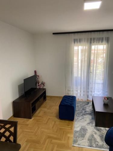 a living room with a tv and a blue ottoman at Maya apartman sa dve spavace sobe in Vrnjačka Banja