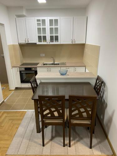 a kitchen with a table and chairs and a sink at Maya apartman sa dve spavace sobe in Vrnjačka Banja