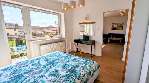a bedroom with a bed and a desk and a window at Słoneczna Przystań - Apartament in Szczedrzyk