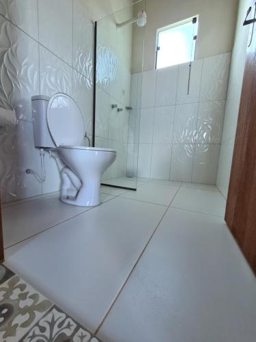 a white bathroom with a toilet and a shower at Bangalôs da Montanha in Serra do Cipo