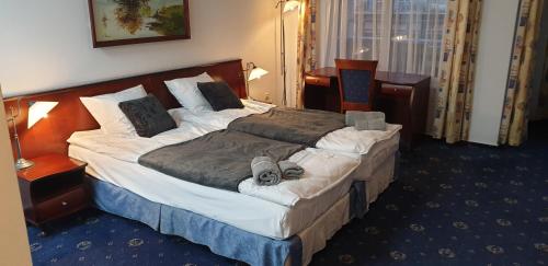 Una cama grande en una habitación de hotel con un perro. en M-Apartamenty w Hotelu Polonia en Kołobrzeg