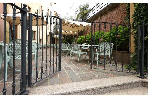a wrought iron fence with tables and chairs on a patio at Hotel Acqui & Centro Benessere in Acqui Terme