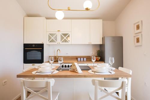 a kitchen with white cabinets and a wooden table with chairs at Apartments Marta in Verunić