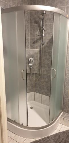 een douche met een glazen deur in de badkamer bij M-Apartamenty w Hotelu Polonia in Kołobrzeg