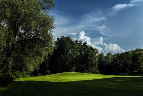 a green golf course with trees and a hole at Tri Duby Golf Apartments in Badín