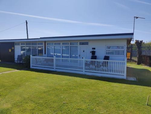 a mobile home with a white fence and a yard at L&L's Lodge, A small but perfectly formed chalet in Chapel Saint Leonards