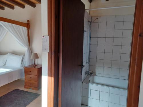 a bathroom with a shower and a bedroom with a bed at Kleanthis House in Tochni