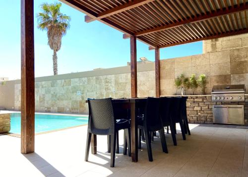 een patio met een tafel en stoelen naast een zwembad bij Ta Lucija - Luxurious 6 Bedroom/En suite Villa - Pool / AC in Santa Luċija