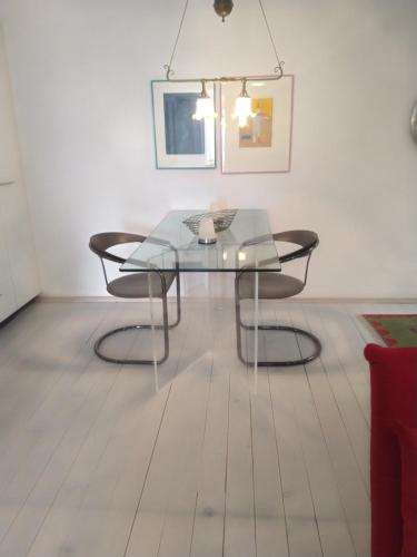 a glass table and two chairs in a room at Swiss Borzoi House in Bellerive