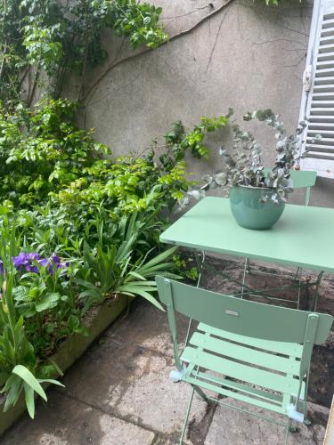 a green table in a garden with plants at L' ALCOVE- Confort Charme Downtown in Dijon