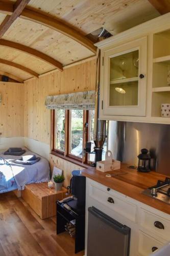 a room with a kitchen with a bed in it at Handcrafted Shepherds Hut in Toppesfield
