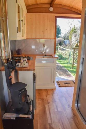 a small kitchen with a sink and a stove at Handcrafted Shepherds Hut in Toppesfield