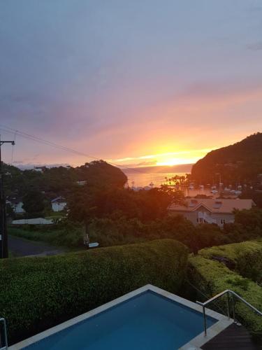 a sunset from the backyard of a house with a swimming pool at Casa Vista in Marigot Bay