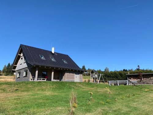 a barn with a black roof on top of a field at Roubenky Hřebečná in Hřebečná