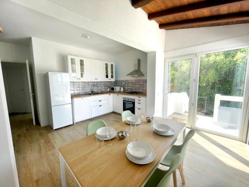 cocina y comedor con mesa de madera y sillas en Naked House Sardinia en Bari Sardo