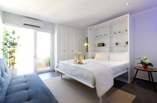 sypialnia z białym łóżkiem i niebieską kanapą w obiekcie Precioso apartamento con vistas al mar y piscinas w mieście Benalmádena
