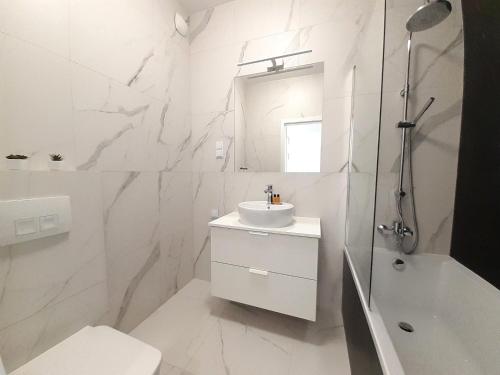 a white bathroom with a sink and a bath tub at Vista Residence Premium II in Warsaw