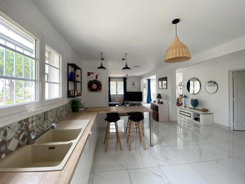 a kitchen with a sink and a counter with stools at Magnifique villa avec piscine in Villeneuve-lès-Maguelonne