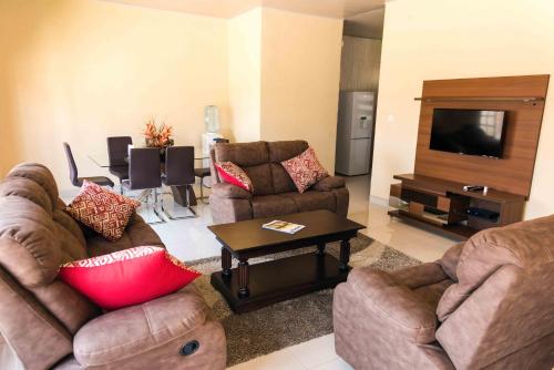 a living room with two couches and a flat screen tv at Luxurious Chimwemwe II - Kat-Onga Apartments in Lusaka