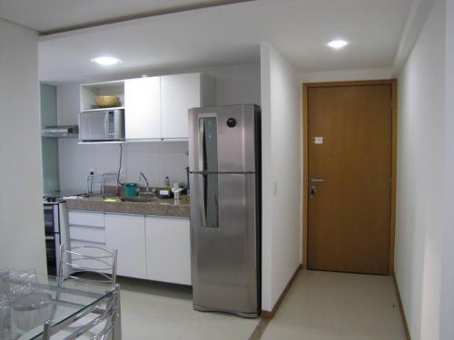 a kitchen with a stainless steel refrigerator in a room at Moderno apartamento perto da praia in Maceió
