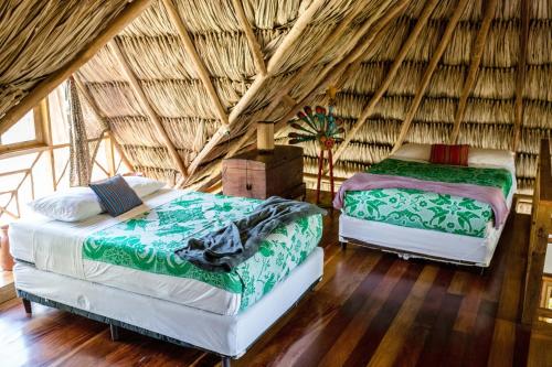 um quarto com 2 camas num quarto com telhado de palha em Pine Ridge Lodge em San Ignacio