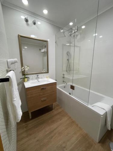 a bathroom with a tub, sink and mirror at Hotel Sete Colinas in Lisbon