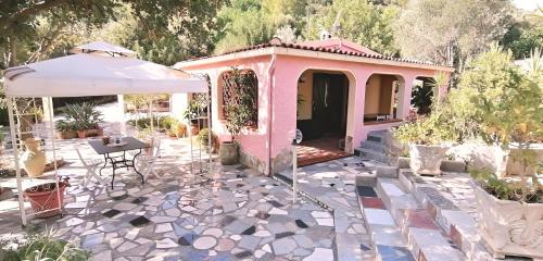 Casa rosa con mesa y sombrilla en Doxina - Belocations, en Sinnai