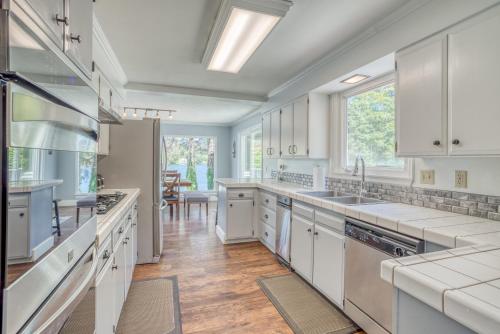 a kitchen with white cabinets and a large window at Laurel Haven - Meredith Lodging in Otis