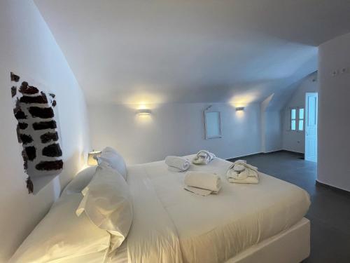 a white bedroom with a bed with towels on it at Marizan Caves & Villas in Oia