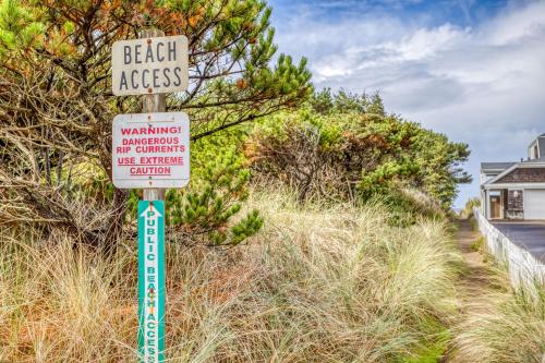 a beach access sign on a pole in the grass at Sea Here - Meredith Lodging in Neskowin