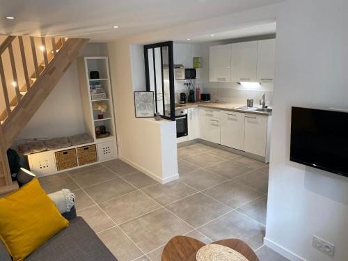 a large kitchen with white cabinets and a television at Le Palm ✧ Duplex centre historique Rouen in Rouen