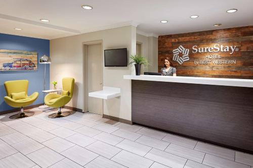 a woman standing at a reception desk in a hotel lobby at SureStay Hotel by Best Western San Diego Pacific Beach in San Diego