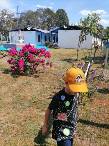 a young child wearing a hat standing in a yard at Hotel campestre la Maria in Villavicencio