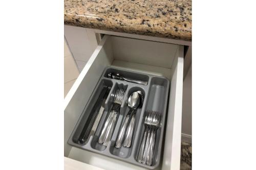 a drawer in a kitchen with forks and spoons at Estúdio charmoso um minuto a pé do mar in Guarujá