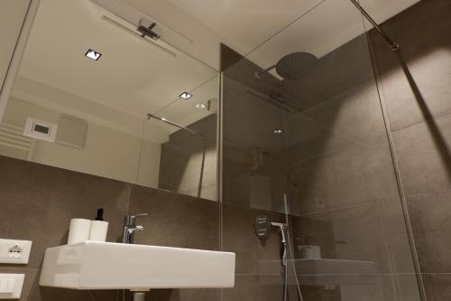 a bathroom with a sink and a shower with a mirror at MUROS - City Modern Living in Trento in Trento