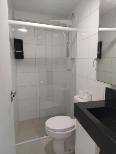 a white bathroom with a toilet and a mirror at Apart um dormitório com vista para estrada da rainha in Balneário Camboriú