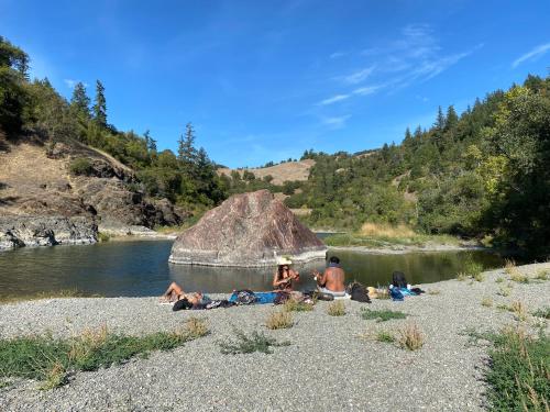a group of people laying on the side of a river at Glamping in the Redwoods with a hot tub! in Garberville