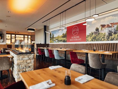 a restaurant with wooden tables and chairs and a large window at Schlosshotel Hellenstein in Heidenheim