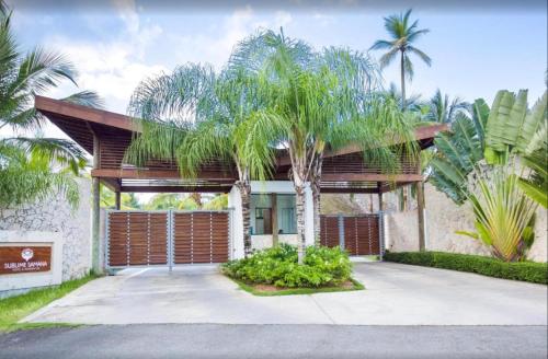 a house with a palm tree in front of it at Apartment in Sublime Samana Résidence in Las Terrenas