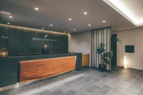 mężczyzna stoi w recepcji w holu hotelowym w obiekcie Hotel Kuretakeso Takayama Ekimae w mieście Takayama