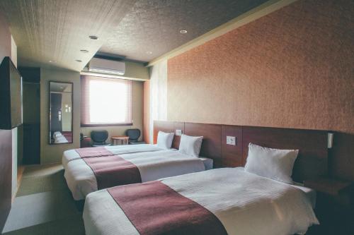 高山市にあるホテル呉竹荘高山駅前のベッド2台と窓が備わるホテルルームです。